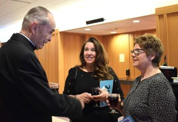 Monsignor Smith, left, talks with Paola Mattera, center, and Patty Huck.