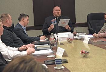 Father Allen Hoffa, commission chairperson and pastor of St. Joseph, Summit Hill, shares some resources and literature with the members of the commission.