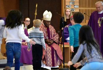 Children from the religious education class welcome Cardinal Ribat to Holy Family.