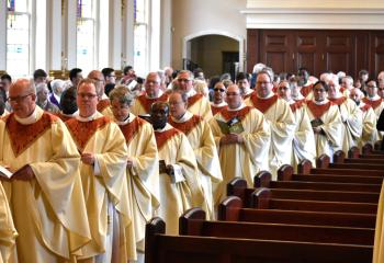 Priests of the Diocese process into the Chrism Mass, a service that was restored in 1967 and dates back to the early 200s. Chrism is created by mixing the soothing oil of balsam with olive oil, in addition to the Bishop breathing on the mixed oil to signify the presence of the Holy Spirit. There are three oils – the oil of catechumens, the oil of the sick and holy chrism – that will be used in the administration of the sacraments throughout the Diocese for the year.(Photo by John Simitz)