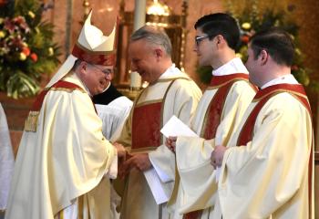 Transitional deacons, from left, John Maria, Giuseppe Esposito and Zachary Wehr receive their call to Holy Orders from Bishop Alfred Schlert during the Chrism Mass.(Photo by John Simitz)