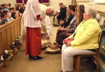Monsignor William Baker performs the Washing of the Feet at All Saints as part of Holy Thursday tradition and ritual. The ritual recalls Jesus, the Son of God, washing the feet of his disciples, symbolizing that he came to serve others and reminds the faithful they are also called to serve others. (Photo by John Simitz)