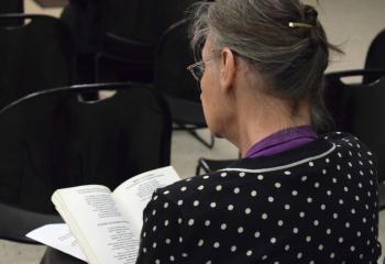 A woman reads Scripture during a visit to St. John XXIII on Holy Thursday. (Photo by John Simitz)