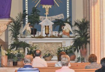 Faithful engage in prayer while visiting St. Joseph, Jim Thorpe on Holy Thursday. Those gathered meditate before statues, crucifixes and saint images veiled in purple cloth. The custom of veiling religious images symbolizes sadness and mourning. (Photo by John Simitz)