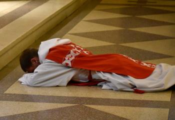 Father Ganser prostrates himself on the altar during the Mass at St. Joseph. “Also in his Passion, Christ gives us the best support he can give us, his Mother. While dying, he gave the woman who walked with him throughout his life and cared for him to his beloved disciple John. In turn, she is present for all of us as a support,” said Bishop Alfred Schlert. (Photo by John Simitz)