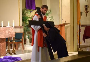 Sisters, Servants of the Immaculate Heart of Mary (IHM) Sister Patricia Michael Godov, pastoral assistant at St. Joseph, venerates the cross held by Father Ganser during the liturgy at St. Joseph. (Photo by John Simitz)