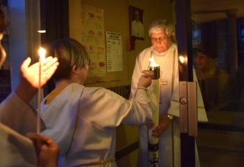 Altar server Alena Muschko lights the Pascal Candle at St. John Fisher. “How can we keep this great news just to ourselves? Today too, let us renew our Baptismal call to Evangelization. Let us carry Christ to all we meet, and see Christ in all we meet. Let us light the world on fire with the love of Christ!” said Bishop Alfred Schlert. (Photo by John Simitz)