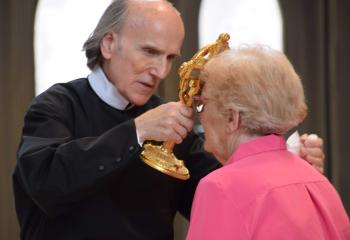 Father Michalik assists a member of the faith in venerating a relic of St. John Neumann.
