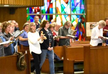 Debbie Rohner, wife of Deacon David Rohner, carries the baby Jesus as the women’s guild processes in on the first night of the mission Palm Sunday evening.