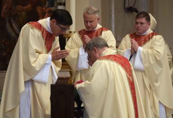 Father Esposito, left, bestows his first priestly blessing to Bishop Schlert. Looking on, are: Father Maria and Father Wehr. (Photo by John Simitz.)