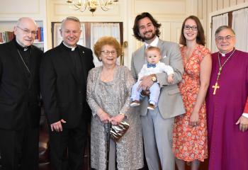 Father Maria, second from left, spends time with family and diocesan officials before his ordination. From left, are: Bishop Cullen; Theresa Maria, mother; his son, James Maria holding his grandson Donato Maria; Abby Maria, daughter-in-law; and Bishop Schlert. (Photo by John Simitz.)