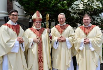 Bishop Schlert, second from left, greets the newly ordained after the ceremony. From left, are: Father Esposito, Father Maria and Father Wehr. (Photo by John Simitz.)