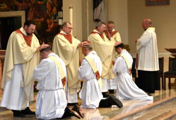 Performing the Laying on of Hands to the newly ordained are, from left: Father Sedar, Monsignor Schoenauer and Father Bortz. (Photo by John Simitz.)
