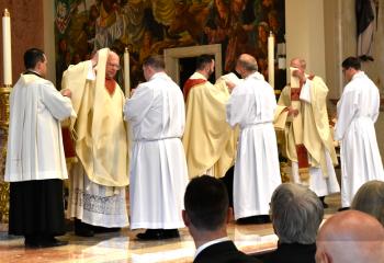 Vesting the new priests during the Investiture with Stole and Chasuble, are, from left: Monsignor James, Father Isaac and Monsignor Orsulak. (Photo by John Simitz.)