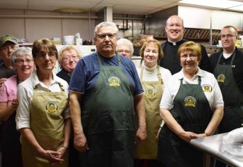 Father Hoffa, back second from right, greets the kitchen staff and volunteers who prepared homemade roast beef, pierogis, meatballs and pastries for the reception.