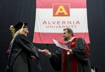 Flynn confers a diploma to an Alvernia student at the commencement, during which he was commencement speaker. (Photo credit Susan Angstadt and Alvernia University)