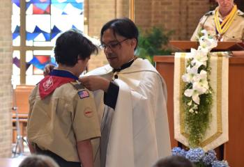 Nolan H receives the Ad Altare Dei award from Father Eric Tolentino as Fred Flemming announces the names of award recipients.