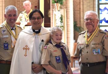The Light of Christ award is given to Corrinne K. From left are Bill Krupka, Father Eric Tolentino and Bernard Hofmann. Fred Flemming is behind them at podium.
