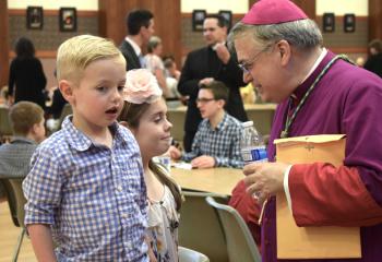 Emmett, 5, and Caesanina, 9, Van Durme, parishioners of Sacred Heart, Bath, chat with Bishop Schlert during the time of fellowship. Father Keith Mathur can be seen in the background.