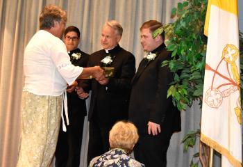 Mary Marzen presents gifts to the new priests on behalf of the Serrans.