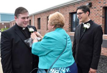 Paulette Roth presents a flower to Father Wehr, left, and Father Esposito.