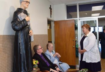 The statue of St. Maximilian Kolbe in a hallway of the school. At left is Alexandria Cirko, assistant superintendent of religious education with the Diocesan Secretariat for Catholic Education.