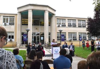 “We’re here because we need a recovery high school – that is a scary reality,” Brooke Tesche tells those gathered with the school entrance behind her.