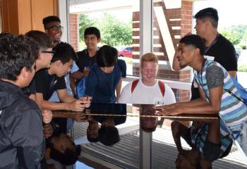 Young men gather around the piano in the DeSales University Center to play and sing a song.