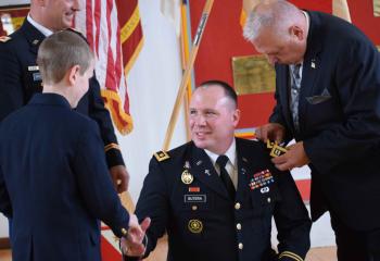 Father Butera receives epaulets from his father, Ralph Butera.