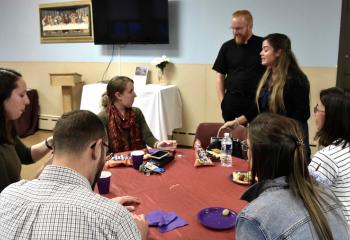 Father Mark Searles chats with young adults at the social.