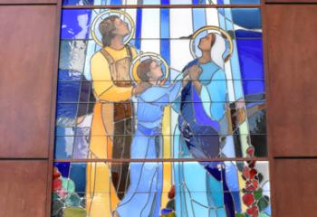 A stained glass window of the Holy Family hangs in the atrium.