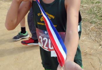 Emmett Rieland from St. Jane Frances de Chantal, Easton shows the medal he received for winning the third- and fourth-grade boys’ race during the meet. (Photo by Ed Koskey)