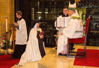 Sister Monica holds the Breviary for the Life of Prayer before Bishop Schlert.