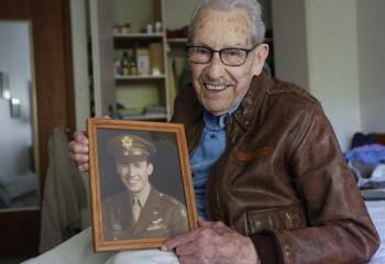 Don Stoulil of Sacred Heart Parish in Robbinsdale, Minn., holds a picture of himself Oct. 30, 2019, which was taken near the end of his tour of duty in World War II as a B-17 bomber pilot. He carried a relic of St. Therese of Lisieux in the cockpit during all of his 31 missions and credits the saint for his survival. (CNS photo/Dave Hrbacek, Catholic Spirit) 
