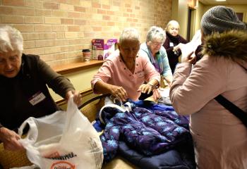 Volunteers – from left, Isabel Koch, Phyllis Johnson and Barbara Quigney – pack up coats for some visitors. 