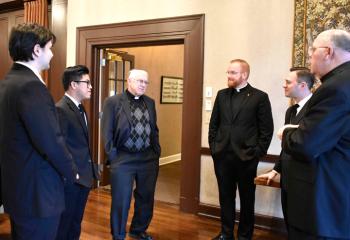 Talking at the luncheon are, from left, Alexander Brown, Anh Do Mai, Monsignor John Grabish, Father Mark Searles, Philip Maas and Monsignor David James.