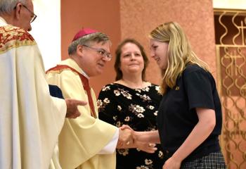 Bishop Schlert presents Emily Olsen with her eighth grade pin. Also participating are Father Joseph Tobias, pastor, and Christine Bruce, principal.
