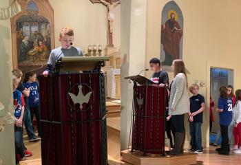 Fifth-graders lead the rosary at Sacred Heart School, Bath: Raymond Grover, left, who started the rosary, and Julian Augello, right, with teacher Allison Hammer.