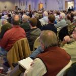 An estimated 600 men listen to a speaker at the conference.